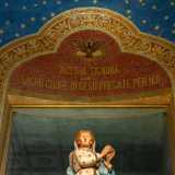 Al centro una ricca cornice vegetale custodisce un mosaico rosso con scritta dorata e piccolo vano che un tempo ospitava il gruppo statuario del Cuore di Maria affiancato dai santi Benedetto e Scolastica